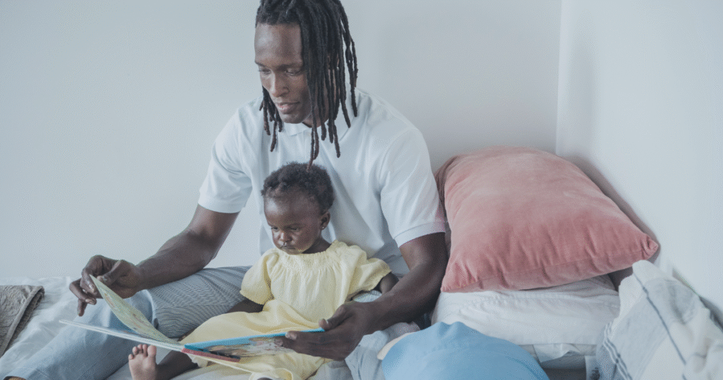 Father with long hair reading a bedtime story to his toddler daughter